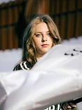Woman framed behind an out-of-focus white fabric foreground