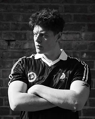 Young man in a striped jersey against a brick wall