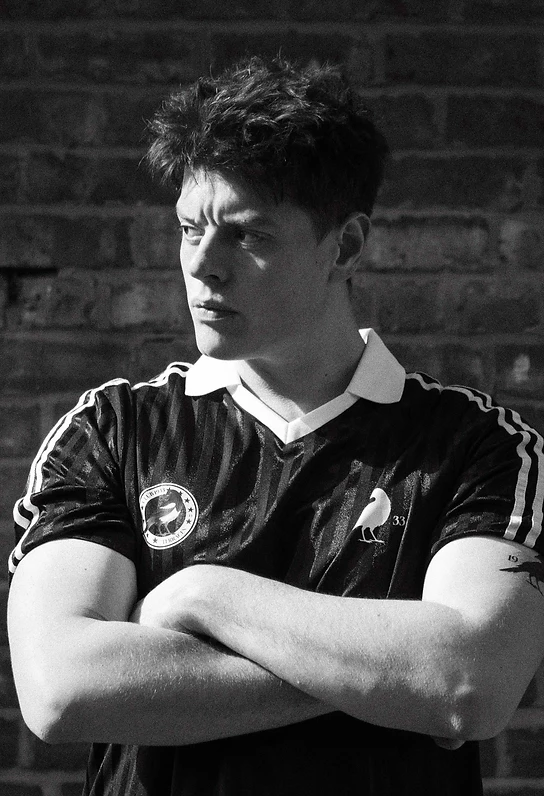 Fan in the Club 1933 jersey against weathered brickwork