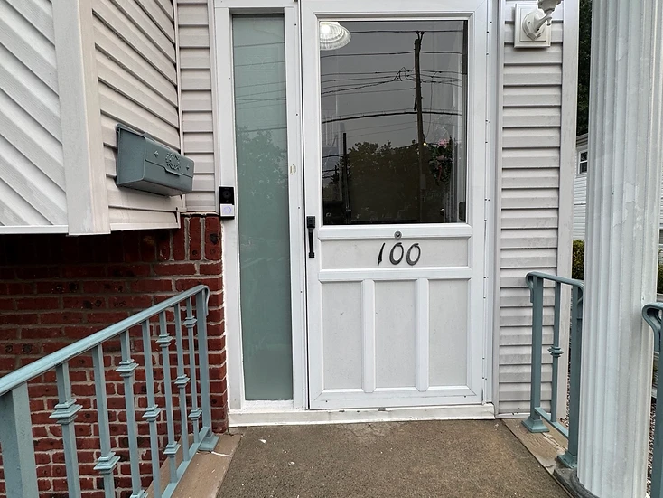 Video doorbell intercom mounted at a residential front entry with sidelight and brick accent