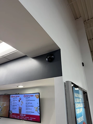 Black dome security cameras installed above a commercial cafe menu board