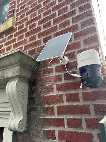 Reolink 4K solar-powered pan-tilt security camera installed on a red brick exterior wall