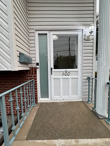 Doorbell camera mounted next to a storm door with house number 100