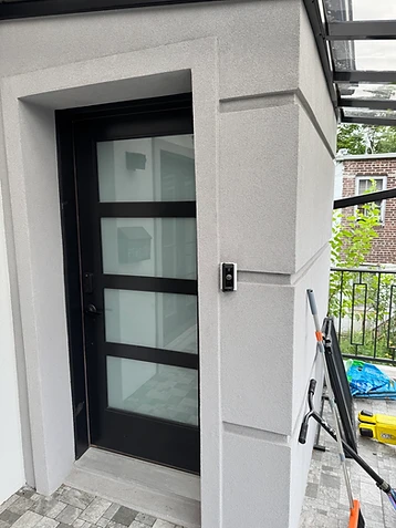 Ring video doorbell at a modern stucco building entrance with a keypad door lock