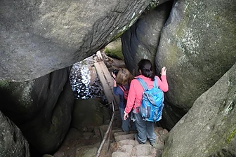 Hikers descending through a rock passage in the Broumov Walls