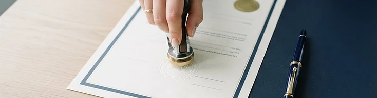A notary seal being placed on a document next to a pen