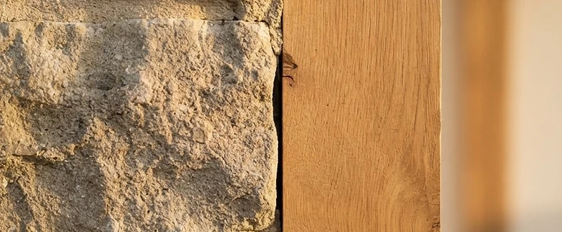 Hand-cut limestone meeting a planed oak beam