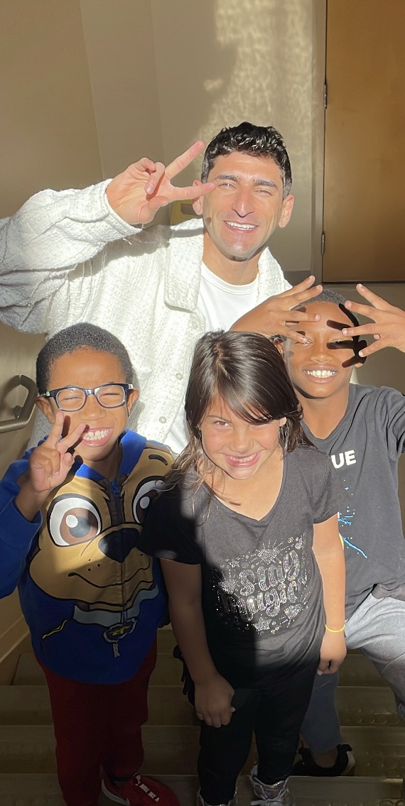 Nasser with three students in a sunlit stairwell