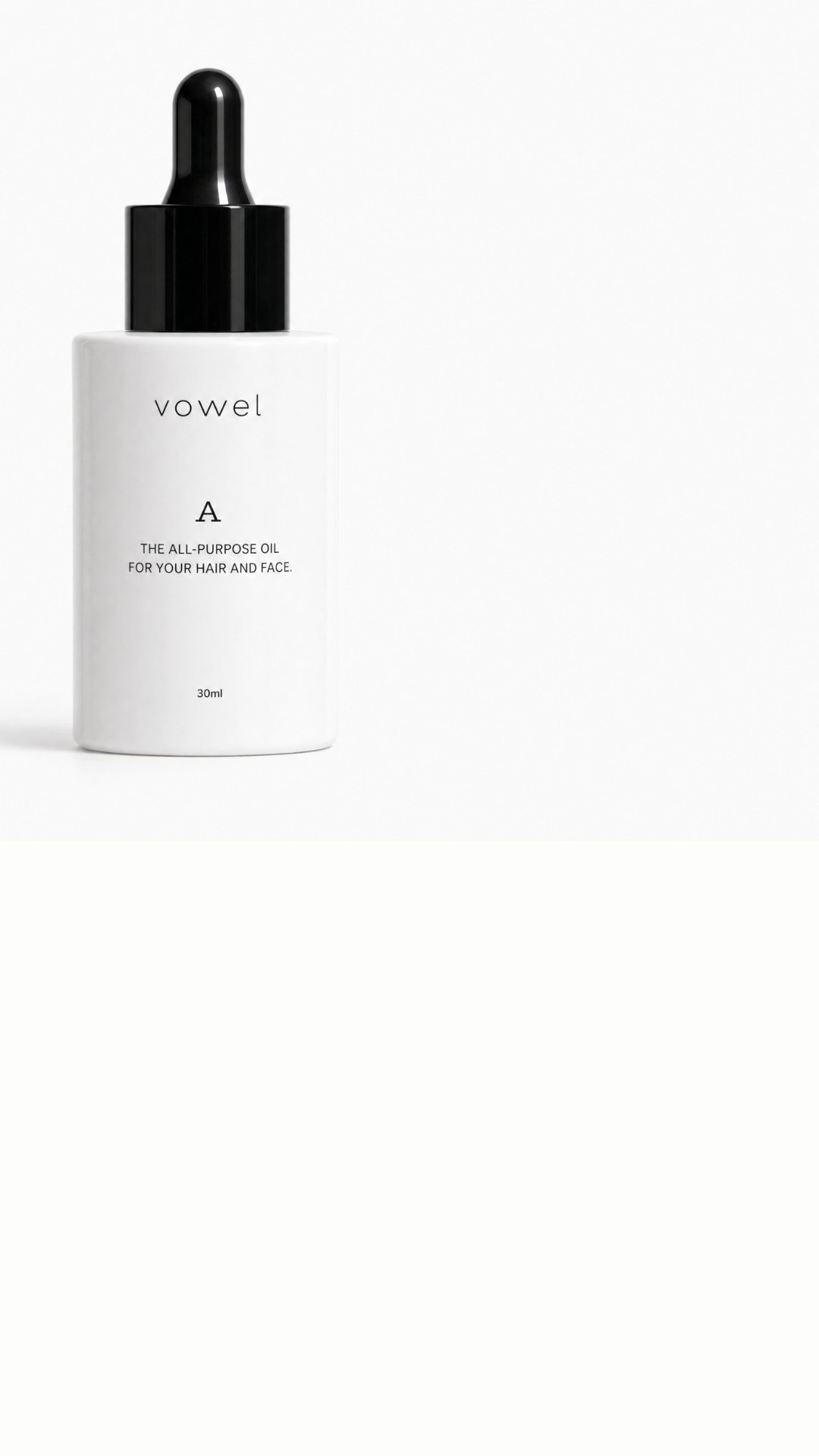The white vowel A oil bottle with a black dropper cap on the left of a clean white surface, with open space to the right