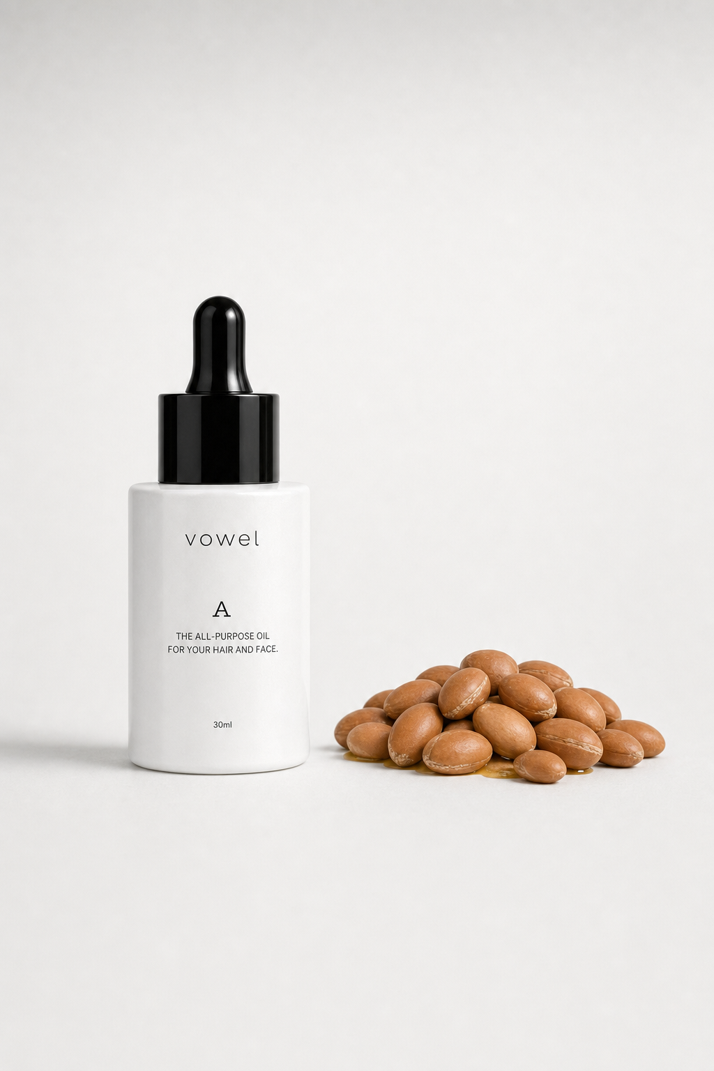 vowel A oil bottle beside a pile of argan nuts