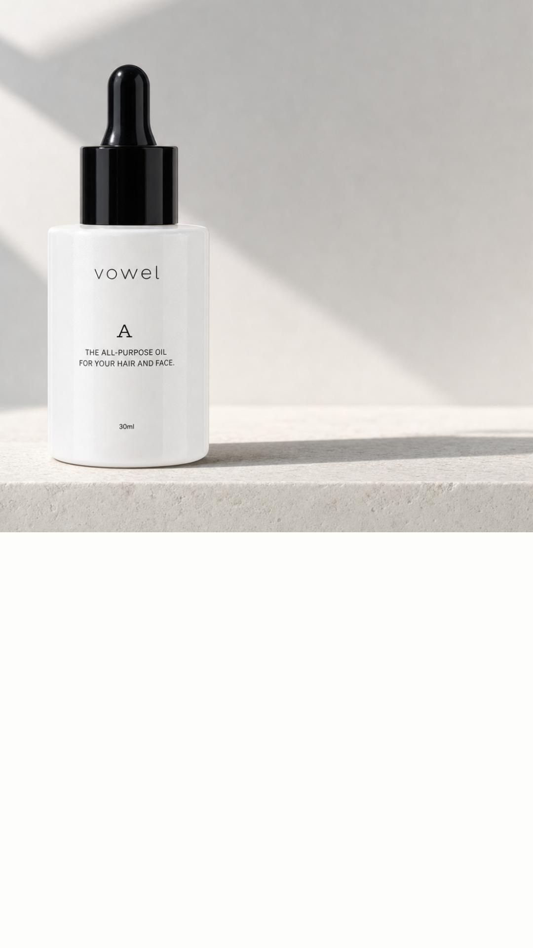 The vowel A oil bottle resting on a stone ledge against an off-white wall
