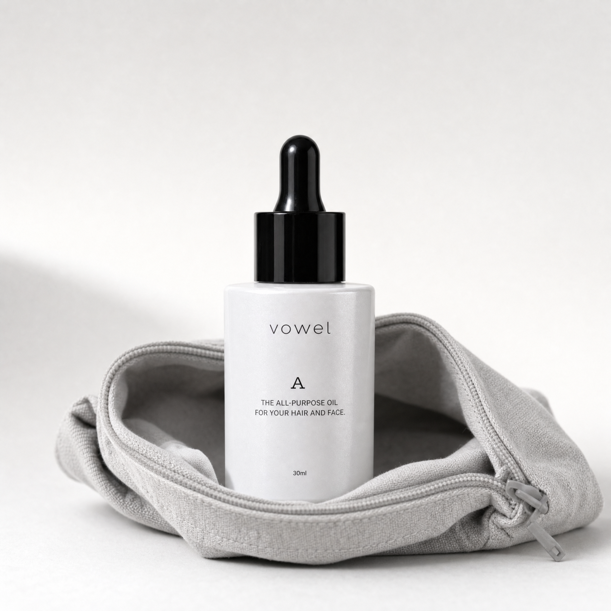 The vowel A bottle wrapped in a grey cloth pouch against a soft grey background
