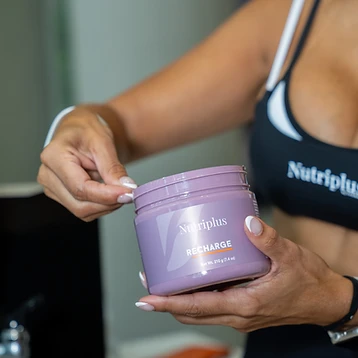 Hands holding a Nutriplus Recharge supplement jar
