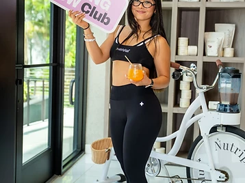 Woman holding a Morning Glow Club sign in a wellness studio