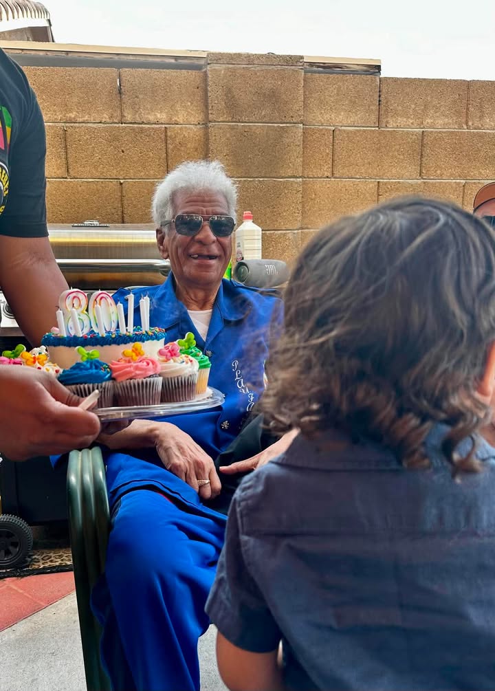 A Daybound member celebrating his 80th birthday with cupcakes surrounded by family