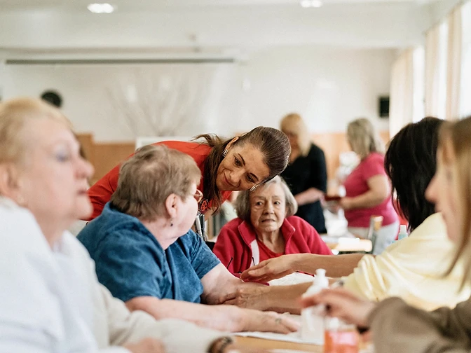 A Daybound facilitator and older adults sharing a warm group activity together at a community table