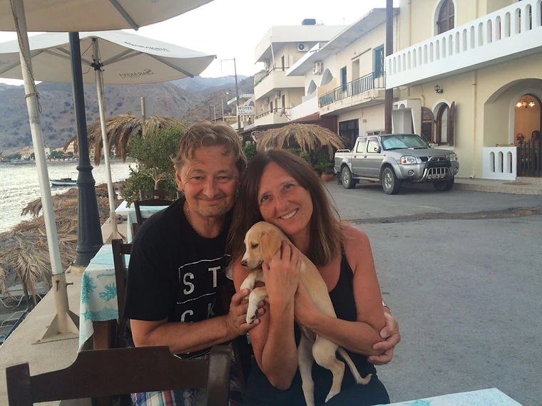 A couple holding a puppy at a coastal restaurant in Crete