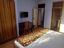 Room with wardrobe, work desk, wall-mounted television and en-suite doorway