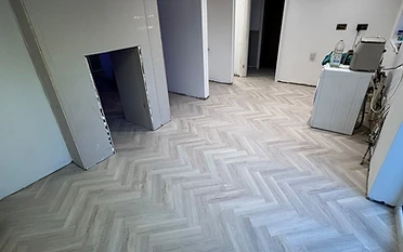 Dos Santos Flooring homepage — herringbone LVT flooring in a sunlit room