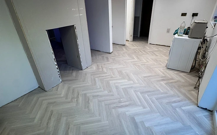 Dos Santos Flooring homepage — herringbone LVT flooring in a sunlit room