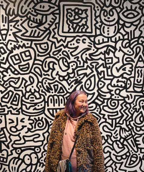 Laura in front of an illustrated wall