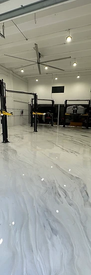 Finished white polyaspartic metallic floor in the same commercial shop — the payoff after the prep