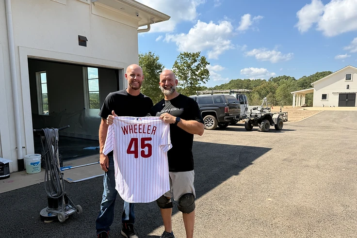 Jeremy Redig and Zach Wheeler holding a Wheeler 45 Phillies jersey in front of a real project site