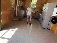 Jeremy standing in a finished polished concrete garage wearing a FloorRescue shirt and gesturing toward the completed space