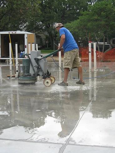 Jeremy Redig running a concrete grinder on a wet slab early in his career