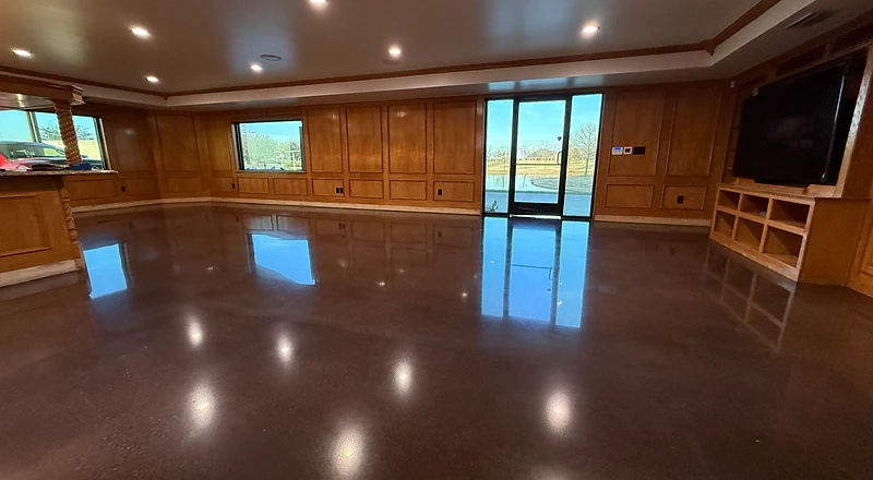 Dark glossy metallic epoxy floor in a wood-paneled room with pond view