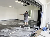 Floor installer rolling a topcoat on a residential garage floor — topcoat and protection system training