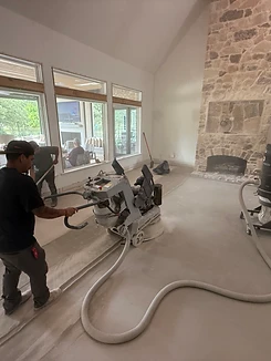 Crew grinding and removing an existing floor overlay with a walk-behind grinder and dust extraction