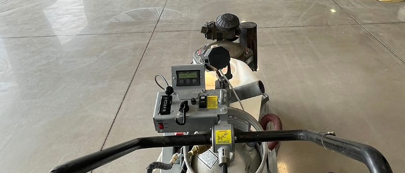 Concrete floor grinder in operation — warehouse scale polishing from behind the handles