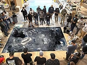 Hands-on epoxy flooring class — installers gathered around a metallic epoxy pour in a warehouse