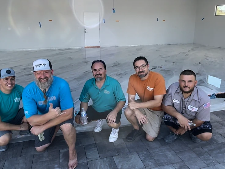 Training event on a freshly installed light grey white poly metallic epoxy floor with installers kneeling on the surface