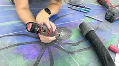Installer using a Milwaukee M12 rotary tool to detail a decorative stained concrete floor