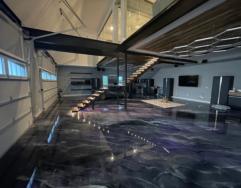 High-end residential garage with metallic epoxy floor, mezzanine, and LED stair lighting