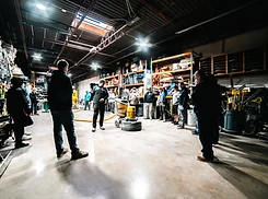 Instructor demonstrating a floor grinder to a group of contractors gathered around the machine in a warehouse training space