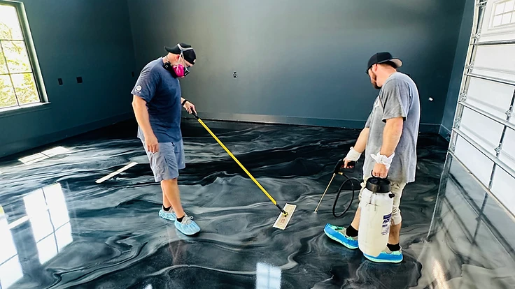 Two workers rolling a metallic epoxy system in a garage — craft in action