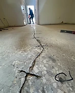 Long jagged crack running through a raw concrete slab before repair