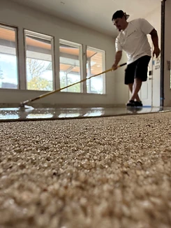 Installer applying a self-leveling overlay with a squeegee across the prepared surface