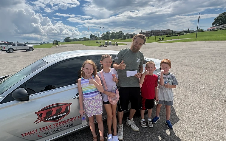 Trey with a family of happy riders beside the Trust Trey car