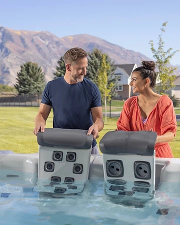 Couple installing a hot tub headrest against a mountain backdrop