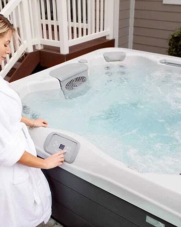 Woman in a bathrobe adjusting settings on a hot tub digital control panel