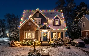 Suburban home at night outlined in warm holiday string lights