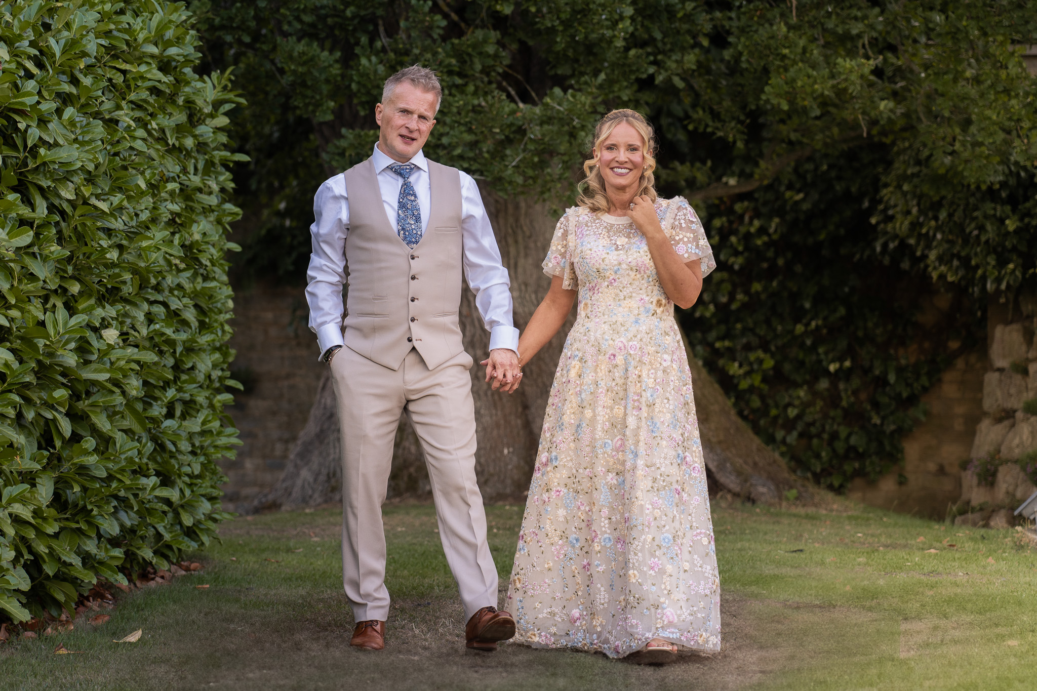 Full-length portrait of bride and groom standing together in the garden at Whittlebury Hall
