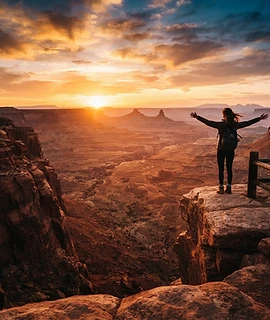 A traveller silhouetted against a glowing canyon vista at sunset