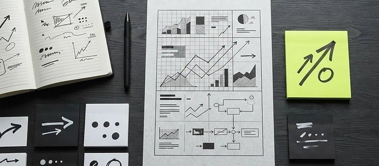 Overhead view of a marketing strategy plan with charts, a notebook and sticky notes