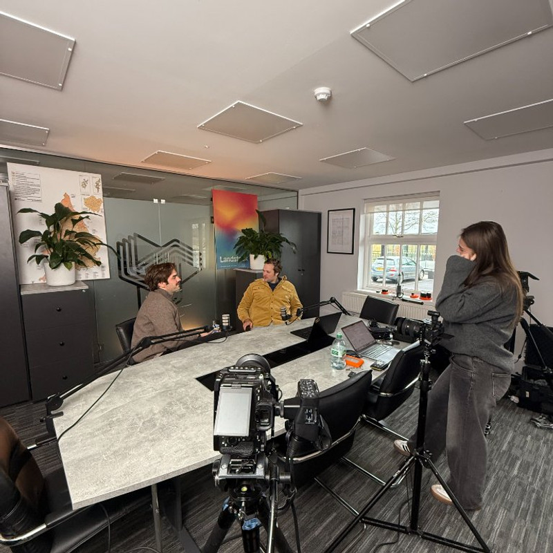 Two-person interview setup on the Landstack shoot, camera in the foreground and the Landstack poster on the wall behind