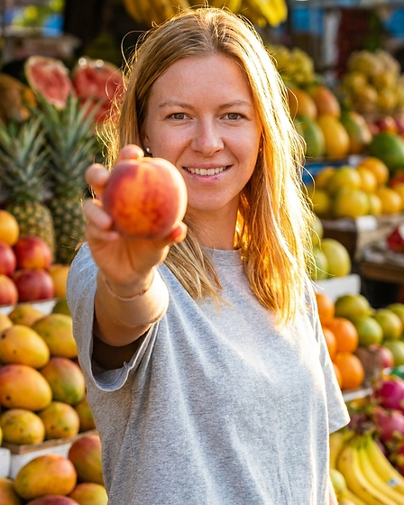 Fien van Fijn Fruit op de fruitmarkt, met een perzik in haar hand